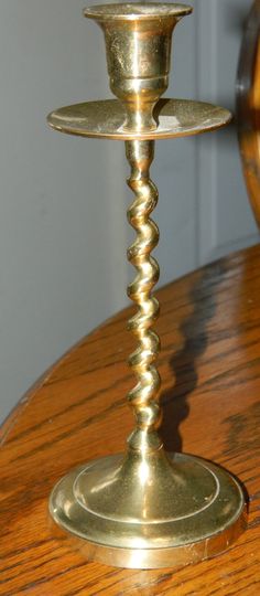 a brass candle holder on top of a wooden table