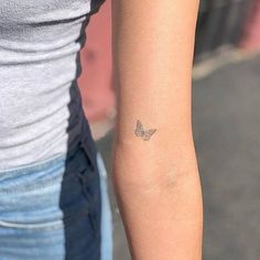 a woman's arm with a small butterfly tattoo on the left side of her arm