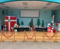 a room decorated for christmas with presents on the floor and red ropes in front of it