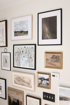 a wall with many framed pictures on it