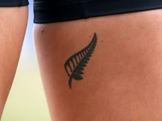 a close up of a person's leg with a tattoo on it that has a fern leaf