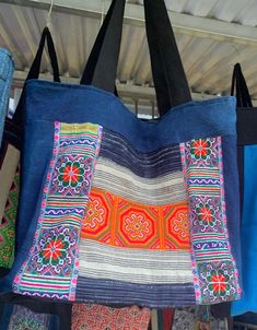 several bags are hanging on a rack in a shop, some have colorful designs and colors