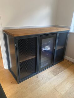 an empty room with two glass doors and a wood top cabinet on the floor in front of a window