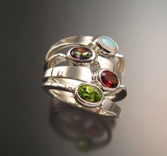 "Set of four Sterling Silver asymmetrical rings with your choice of 4mm x 6mm oval natural birthstones.(restrictions apply) Four rings are about 8-9mm wide at the bottom and 15 - 16mm at the top. Mixed shapes and premium stones are extra. Specify size and stone preference in a \"note to seller\" at check-out. It is always best to send a note to work out the details before ordering." Multi-stone Stackable Rings, Modern Oval Sterling Silver Birthstone Ring, Modern Oval Birthstone Ring In Sterling Silver, Silver Oval Multi-stone Stackable Rings, Mothers Birthstone Ring, Asymmetrical Ring, Birthstone Ring Mothers, Rings Handmade, Silver Rings Handmade