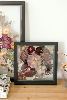 an arrangement of flowers is displayed next to a framed photograph