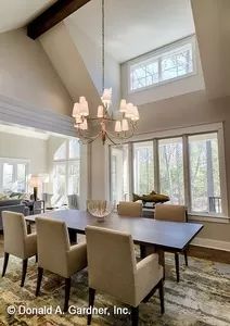 a dining room table with chairs and chandelier in front of two large windows