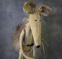 a stuffed animal rat is posed on a table top with its head turned to the side