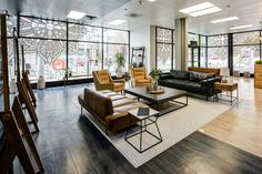 a living room filled with lots of furniture next to tall glass windows on the wall