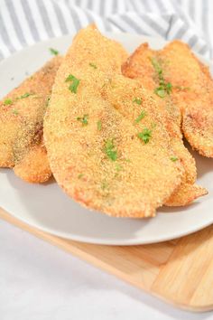 some fried food on a white plate with parsley sprinkled over the top