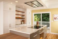 a kitchen with white cabinets and an island in the middle is seen from across the room