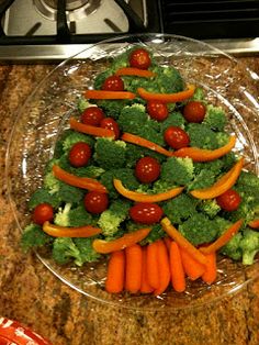 a christmas tree made out of carrots and broccoli on a clear plate