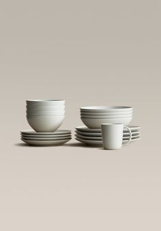 a stack of white cups and saucers sitting next to each other on a table