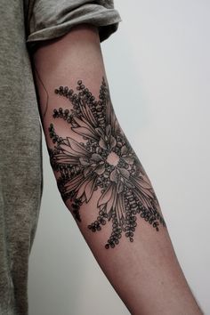 a person with a tattoo on their arm that has flowers and leaves in the middle