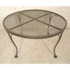 a round metal table with mesh top