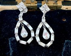 "Incredible pair of vintage 1980s rhinestone bling drop earrings. 4 stones clustered to make a form a square at the earlobe then features an oval chain drop of bar shaped rhinestones centered around a pear drop solitaire. The setting is a bright silver tone metal. Sure to grab attention. Sturdy screw back earrings to loosen and tighten in place. No visible designer or makers mark is visible or found. These vintage earrings have been meticulously stored over the years and originate from a smoke free home. They are beautifully designed and will add the right amount of bling for your special occasion. These heirloom quality earrings are timeless and would be wonderful to compliment your wedding jewelry ensemble. Excellent condition - all stones are intact. Measures 1.5\" top to bottom x .58\" Vintage Sparkling Stone Drop Earrings, Vintage Jewelry With Sparkling Stones In Drop Earrings, Earrings Crystal, Vintage Clip, Screw Back Earrings, Vintage Earrings, Makers Mark, Crystal Earrings, Crystal Rhinestone