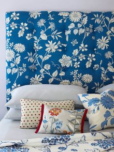 a bed with blue and white flowers on it's headboard, pillows and blankets