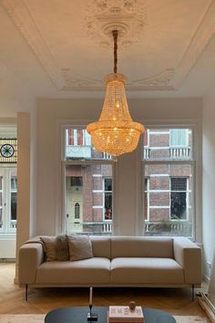 a living room filled with furniture and a chandelier hanging over the top of it