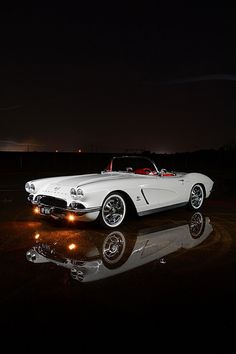 a white car parked in the dark with its lights on