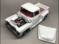 a toy truck with an engine in the bed and hood up on it's flatbed