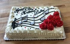 a sheet cake decorated with music notes and red roses is on a wooden table top