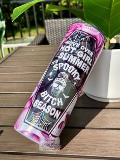 a can of beer sitting on top of a wooden table next to a potted plant