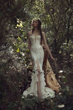 a woman standing in the woods wearing a white dress