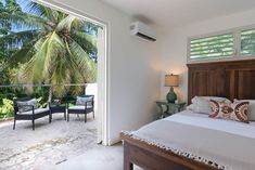 a bed sitting next to a window in a bedroom under a palm leaf covered skylight