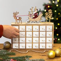 a wooden calendar with reindeers and sleigh on it next to christmas decorations