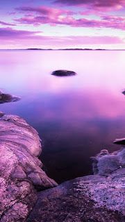 some rocks water and pink clouds in the sky