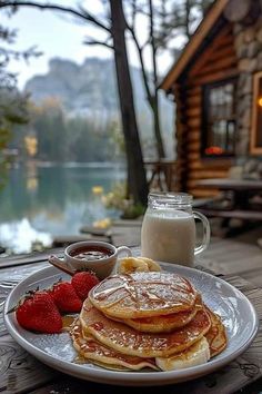 pancakes with syrup and strawberries on a white plate next to a glass of milk