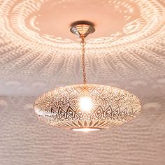 a light fixture hanging from the ceiling in a room with an intricate design on it