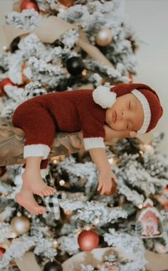 a baby laying on top of a christmas tree