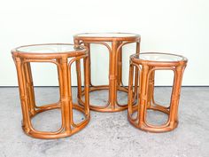 three tables made out of rattan with glass tops on concrete flooring area next to wall