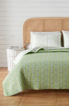 a bed with green bedspread and pillows on top of it in a room