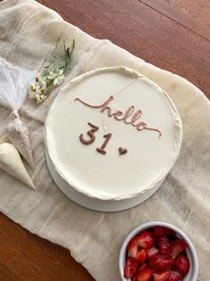 a cake with the word hello 51 written on it and strawberries in a bowl