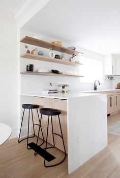 a kitchen with two stools next to an island in the middle of the room