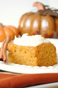 a piece of cake sitting on top of a white plate next to some pumpkins