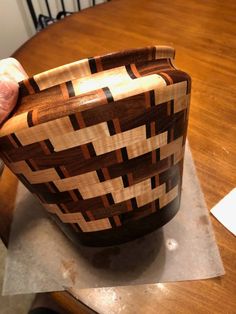 a wooden bowl sitting on top of a table next to a person's hand