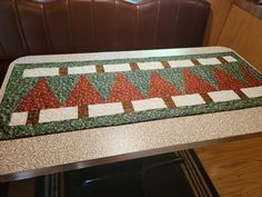 a quilted table runner on top of a dining room table with brown leather chairs