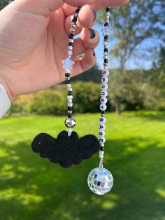 a hand holding a black and white necklace with a mickey mouse charm hanging from it