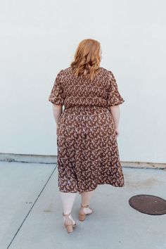 Stay stylish with the Emsley Midi dress! Featuring a charming brown color with delicate white florals, this dress is designed with a smocked bodice and flared bubble sleeves for a fun and flattering look. Plus, it has pockets for added convenience. Look effortlessly chic in this must-have dress! The Emsley Midi is lined. Fits true to size. Model is wearing a small and is 5'10". Plus model is wearing a 2X and is 5'6". Size Chart Length Bust Waist S 46" 30" 28" M 46" 32" 30" L 47" 34" 32" XL 48" 3 Brown V-neck Dress For Garden Party, Brown Modest Midi Dress For Spring, Modest Brown Midi Dress For Spring, Brown Midi Length Dress With Smocked Back, Brown Ruffle Hem Midi Dress For Spring, Brown Short Sleeve Dress For Garden Party, Spring Brown Smocked Dress, Spring Brown Flowy Midi Dress, Spring Brown Midi Dress With Smocked Bodice