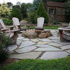 a stone patio with chairs and rocks in the middle