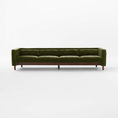 a green velvet couch with wooden legs on a white background, it is in the shape of an l - shaped sofa