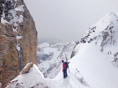 two people standing on the side of a snow covered mountain with their arms in the air