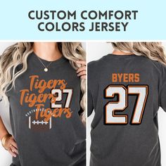 Show your team spirit with this custom Comfort Colors tshirt perfect for GAME DAY! Customize not only your color, but your school name, and player number. :)  HOW TO ORDER SHIRTS 1. REVIEW ALL PHOTOS for size and color options, as well as shop policy. 2. CHOOSE SHIRT SIZE from the drop-down menu. Notice the size guidance graphic if you want the trendy oversized look.  3. CHOOSE SHIRT COLOR from drop-down menu. 4. INSERT PERSONALIZATION 5. ADD TO CART (If ordering multiples, repeat steps 2-5) 6. CHECKOUT after carefully reviewing your cart. We welcome questions so please don't hesitate to send us a note.  PRODUCT MATERIAL DETAILS: Comfort Colors garments UNISEX and are made 100% with ring-spun cotton. The soft-washed, garment-dyed fabric brings extra coziness to your wardrobe while the rela Collegiate Sublimation Design With Name Print For Sports Events, Team-colored Crew Neck T-shirt For Cheerleading, Varsity T-shirt With Team Name For College, Collegiate T-shirt With Name Print For Fans, Customizable T-shirt For Football Season, Customizable Sporty Sublimation Design For College, Customizable Sporty College Apparel With Sublimation Design, Varsity Cotton T-shirt With Custom Print, Varsity T-shirt For College Football Season