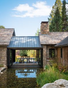 a house with a pond in front of it and stone walls around the back yard