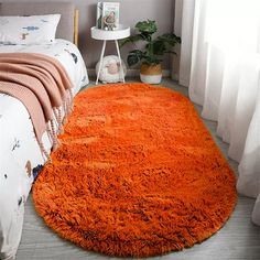 an orange rug is on the floor next to a bed