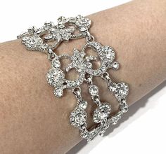 "A Victorian style bridal bracelet with ornate damask curls and motifs, made of clear swarovski crystals, set on tarnish resistant silver rhodium plated base. It has flexible joints. Bracelet crystal is 1 1/2\" (4cm) wide. * Limited edition. While supplies last only. * View matching pieces or similar designs at https://etsy.me/2sewmK9 View all bracelets at https://etsy.me/S9RHlf" Wedding Filigree Adjustable Bracelets, Silver Filigree Bracelets For Wedding, Adjustable Filigree Bracelets For Wedding, Glamorous Silver Bracelets For Wedding, Ornate Bangle Bracelets For Wedding, Old Hollywood Vintage, Hollywood Vintage, Damask Wedding, Vintage Wedding Jewelry