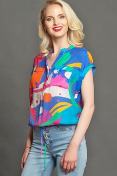 Rolled flutter sleeve woven blouse with functional button placket  and draw string waist closure in Bright multi color print. Fashion; women's fashion; women style; casual style ; tops; casual fashion; fashion ideas; style inspiration, style ideas;  trendy outfits; Fashion for work; summer fashion; spring fashion; trends 2020; #fashion #classyfashion #fashionideas #styleinspiration #styleideas #fashionTrends #fashionInspiration #elegantfashion #fashionstyle #tops #evafranco Casual Summer Blouse With Tie Waist, Short Sleeve Drawstring Top For Beach, Short Sleeve Drawstring Top For Vacation, Short Sleeve Top With Drawstring For Vacation, Drawstring Short Sleeve Tops For Beach, Casual Multicolor Print Tops For Workwear, Colorful Printed Casual Blouse, Casual Multicolor Printed Blouse, Casual Beach Tops With Drawstring Tie