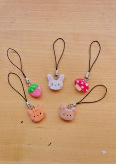 four different shaped key chains with animals on them, one has a strawberry and the other has an animal face